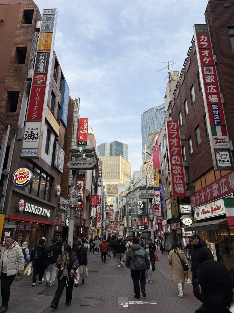 Busy Shibuya Center Gai shopping street lined with tall red and white karaoke and restaurant signs