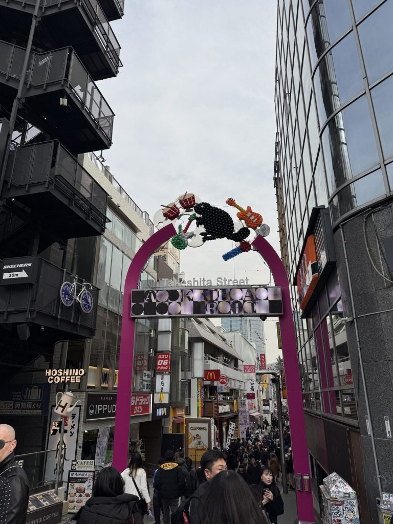 The colorful arch at the entrance of Takeshita Street in Harajuku, with crowds and shop signs stretching down the street
