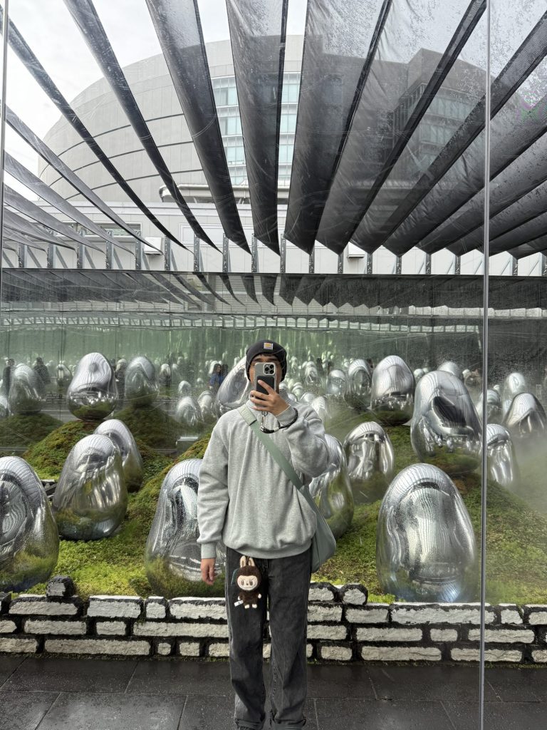 Mirror selfie in front of the moss garden at teamLab Planets, with silver egg-shaped sculptures sitting on green moss